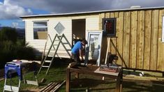 a man working on the side of a tiny house