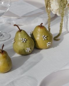 three pears sitting on top of a white table cloth