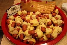 a red plate topped with hot dogs covered in mustard and ketchup on top of a counter