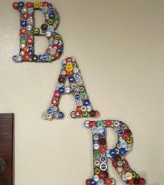 two letters made out of bottle caps are hanging on the wall next to a mirror