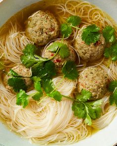 meatballs and noodles are in a white bowl with parsley on the rim, ready to be eaten