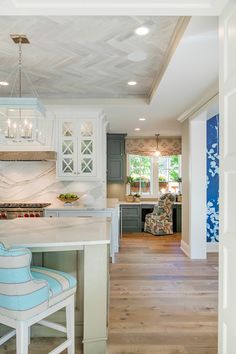 a kitchen with white cabinets and blue accents on the countertop, along with two stools