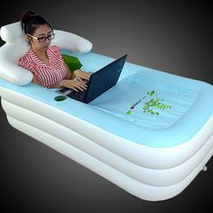 a woman sitting in an inflatable pool using a laptop