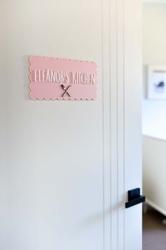 a pink sign on the side of a white wall that says eleanor's kitchen