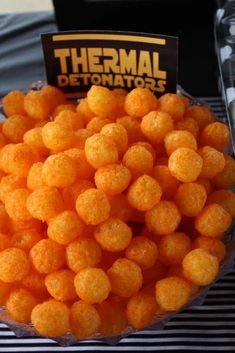 a bowl filled with cheetos sitting on top of a table next to a sign