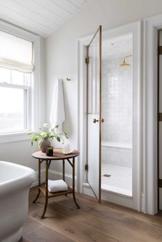 a bathroom with white walls and wood floors