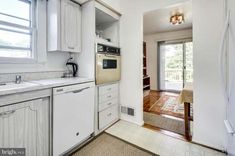 a kitchen with white cabinets and an open door leading to a patio area that leads into the dining room