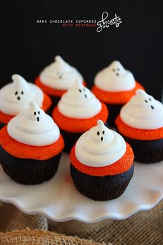 halloween cupcakes with white frosting and ghost faces on top are sitting on a plate