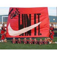 a group of cheerleaders posing in front of a giant banner