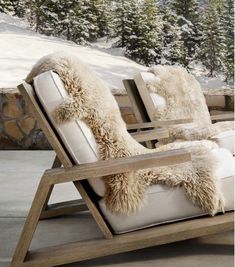 two chairs with furry cushions sit in front of a snowy mountain scene and pine trees