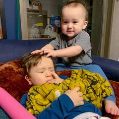 two small children laying on top of a bed next to each other, one is touching the head of another child