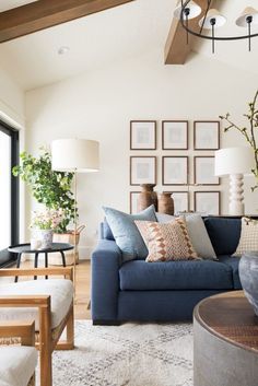 a living room with blue couches and pictures on the wall above them, in front of a large window