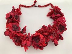 a red crocheted necklace with flowers on it