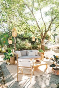 an outdoor living area with furniture and trees in the background, surrounded by greenery