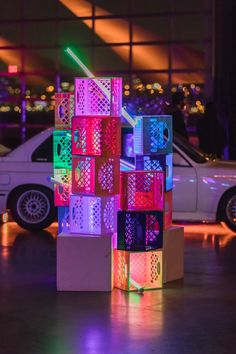 a white car parked in front of a building with colorful lights on it's sides