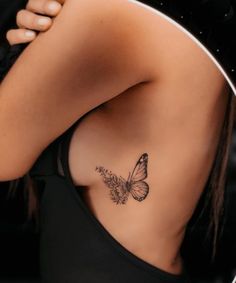 a woman's back with a butterfly tattoo on her left side ribcage