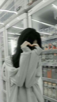 a woman standing in front of a store shelf with her hands to her face and looking at the camera