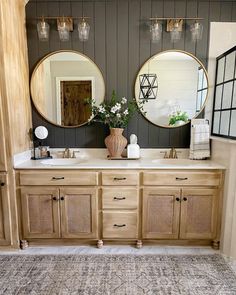 a bathroom with two round mirrors above the sinks and wooden cabinetry on the wall