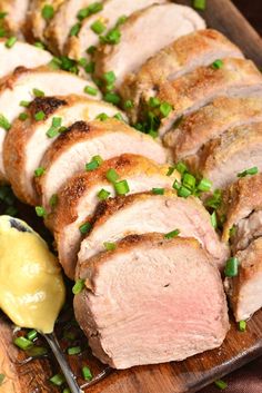 sliced pork with green onions and mustard on a plate