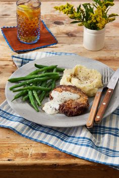 a plate with meat, mashed potatoes and green beans