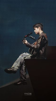 a young man sitting on top of a chair holding a guitar in his right hand