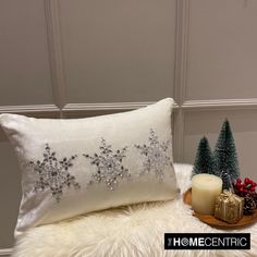 a white pillow with silver sequins on it next to a candle and christmas tree