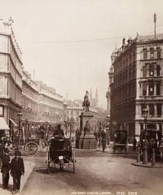 an old black and white photo of people on the street with horse drawn carriages in front of buildings