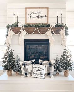 a fireplace decorated for christmas with greenery and stockings on the mantel above it