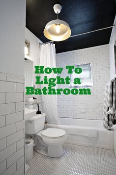 a bathroom with black and white tile flooring and green text over the image that reads how to light a bathroom