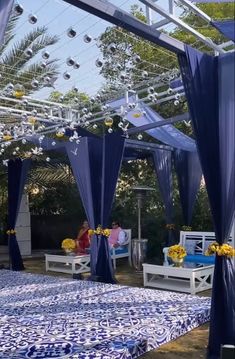 a blue and white bed sitting under a canopy next to a lush green park filled with trees