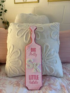 a pink bottle shaped pillow sitting on top of a bed next to a white pillow