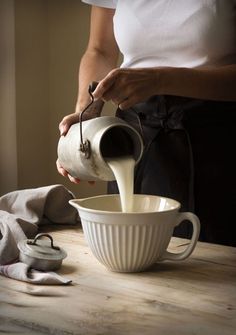 a person pouring milk into a white bowl