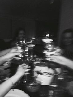 black and white photograph of people toasting with wine glasses on a dining room table