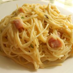 a white plate topped with spaghetti and ham