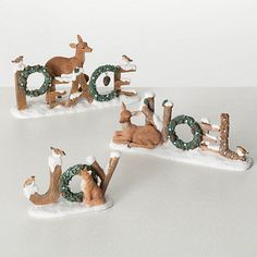 three small figurines sitting on top of snow covered letters that spell out the word joy