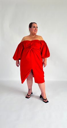 a woman in a red dress is posing for the camera with her hands on her hips