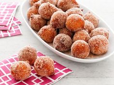 powdered sugar coated doughnuts in a white bowl on a pink and white napkin