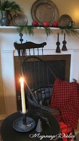 a lit candle sitting on top of a table next to a chair and fire place