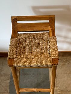 a wooden chair with woven seat and backrests on concrete floor next to wall