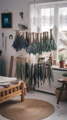 dried herbs hanging from the ceiling in a room next to a bed with a rug on it