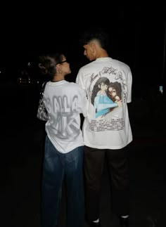 a man and woman standing next to each other in front of a dark sky at night