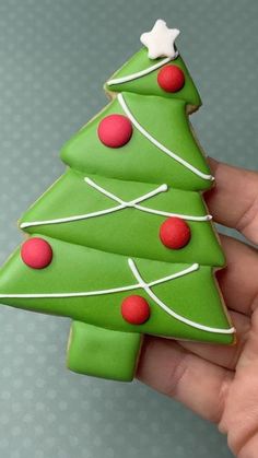 a hand holding a decorated christmas tree cookie