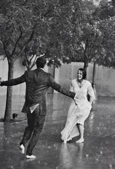 two people are dancing in the rain under trees