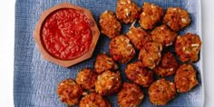 some meatballs and ketchup are on a blue cloth next to a small bowl