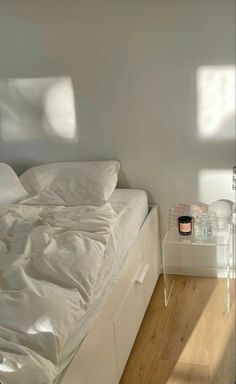 a white bed sitting in a bedroom next to a window with sunlight streaming through it