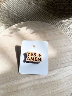 a wooden pin with the words yes and amen on it sitting on a table