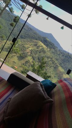 a bed with a colorful blanket on top of it and mountains in the back ground