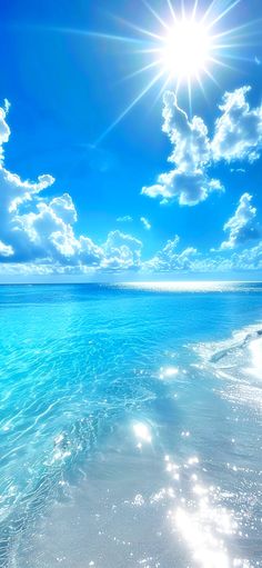 the sun shines brightly over an ocean beach with clear blue water and white clouds