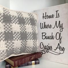 a pillow sitting on top of a book next to a sign that says home is where my bunch of crochets are