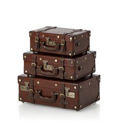 three brown suitcases stacked on top of each other in front of a white background